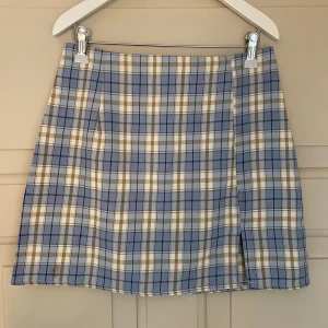 Rutig minikjol - En blårutig tight minikjol men dragkedja baktill och en liten slit framtill. Säljer då den inte kommer till användning länger (inga defekter)