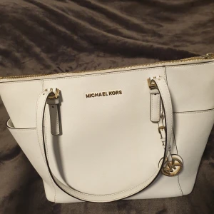 Michael Kors väska - Vit äkta Michael Kors väska med guld detaljer. Tecken på användning finns med den är i gott skick. Köptes på Zalando och nypris ligger på 2500 kr.