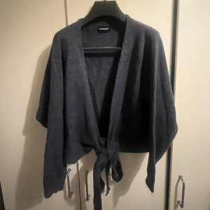 Blå stickad tröja - Säljer den här snygga stickade tröjan som man knyter. Har bara blivit använd ett par gånger 