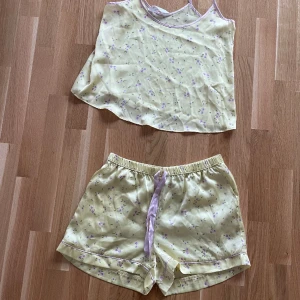 Blommigt pyjamas set - Säljer denna jättesöta siden pyjamasen. Shortsen är använda ett par gånger och toppen är helt oanvänd. Strl XS men skulle säga att den passar S/M.