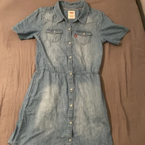 Jeansklänning - En riktig fin jeansklänning från Levis. Använd kanske 2 gånger. Passar storlek xs och mindre om den ska sitta lite oversized.