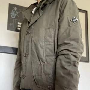En olivgrön Field jacket från J.lindeberg i storlek XL men passar L. Jackan har några defekter dock inga synliga. 