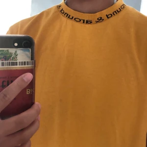 Senapsgul t-shirt - Urban Outfitters - Jättesnygg och skön senapsgul t-shirt från Urban Outfitters. Med text runt hela kragen där det står ”Around & around” på. I mycket gott skick! Möts upp i stockhom, annars står köparen för frakt:)