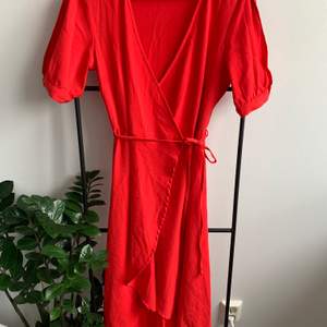 Fin omlott klänning med möjlig justering med snörena, har fin liten detalj på ärmarna med en slits. Faller fint och fin röd färg!