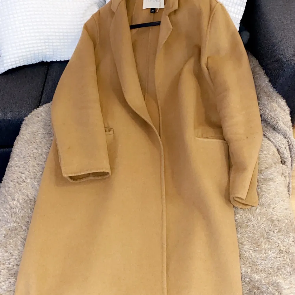 Väldigt lång kappa i beige/brun färg i tunn material passar perfekt till stickad tröja till höst har används flitigt.. Jackor.