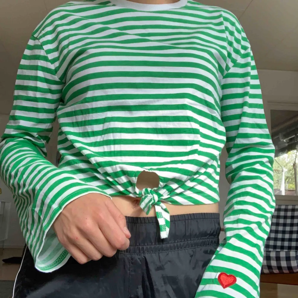 En grön randig långärmad t-shirt med vida ärmar, med ett litet gulligt hjärta på armen. Köpt i Danmark för 200kr. Toppar.