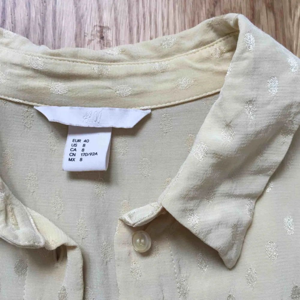 Ljusgul skjorta från H&M. Blanka prickar i tyget. Hel och ren, men kanske skulle må bra av att strykas ordentligt. . Skjortor.