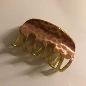 Hårklämma  - Guldig hårklämma med rosa ”leopardfläckar” på. Har en spricka som ni kan se på andra bilden, men annars gott skick😊                                                                               10kr+frakt, kan mötas i Vasastan 