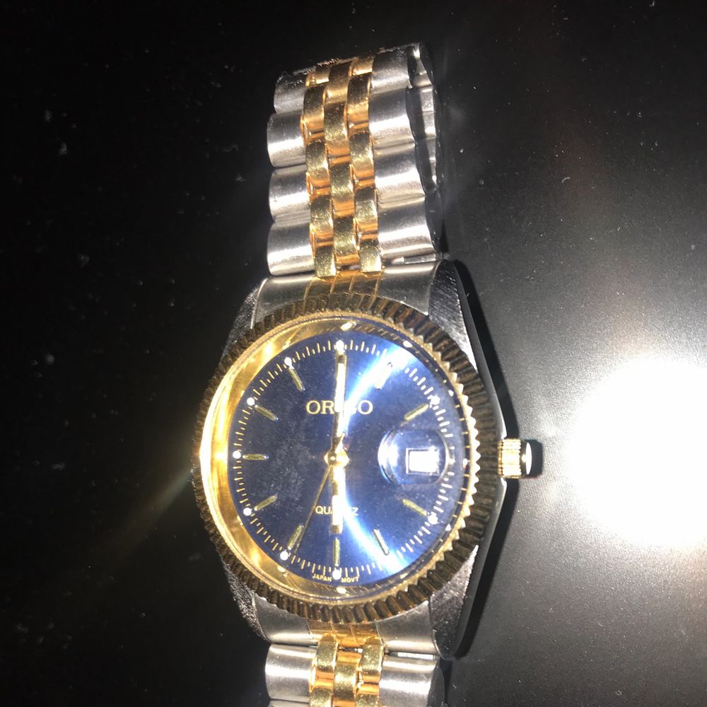 Säljer då det var en present till min pojkvän men den passade tyvärr inte. Klockan fungerar super och är i nyskick. Märke Origo. Klockan har ett silver och guld färgat armband. Urtavlan är navy (mörk blå) med markeringar. Spännet är ett viklås.. Accessoarer.