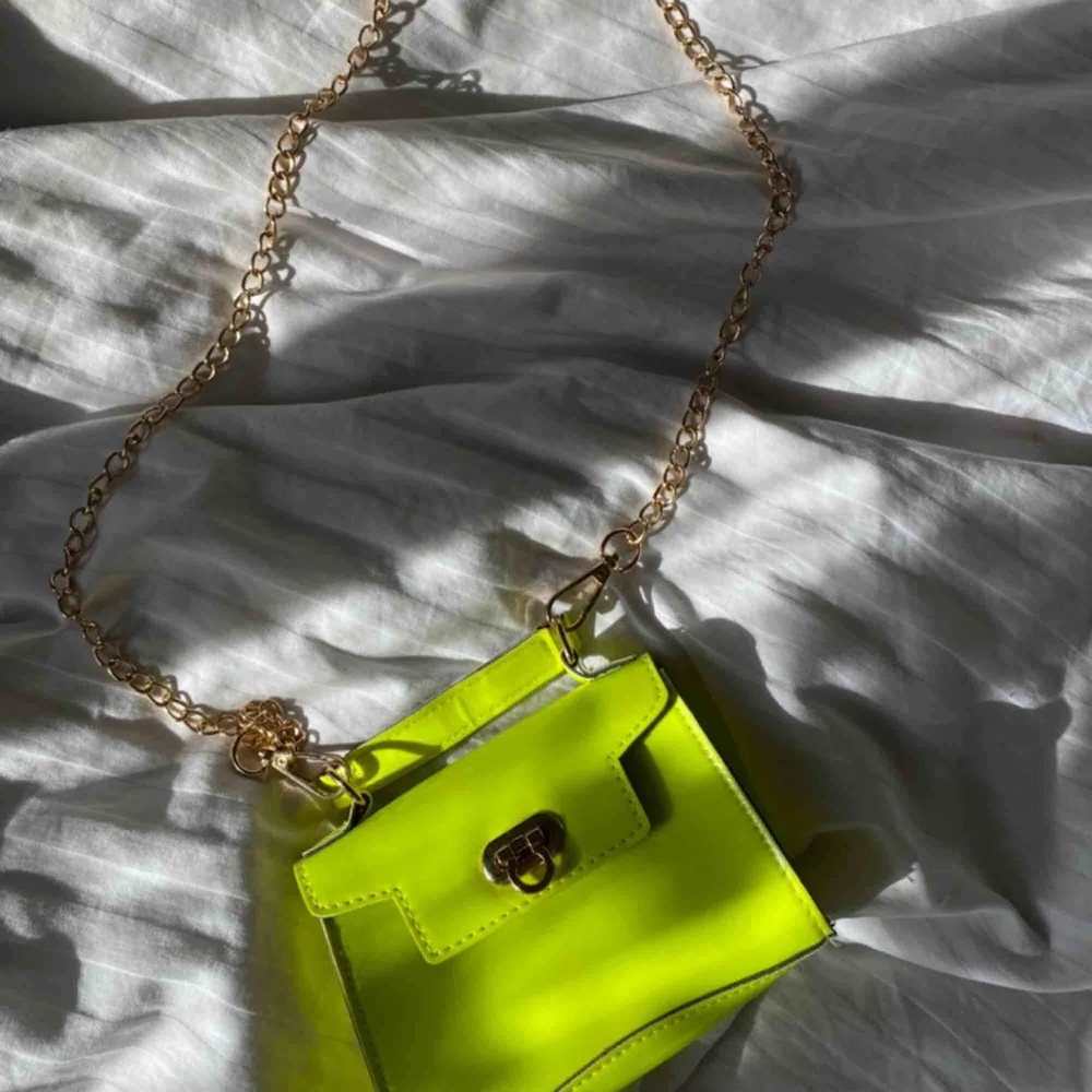 Liten väska i neon gul/grön med guld kedja! Köpt för ett tag sedan men är ej använd. Skriv till mig om du är sugen! . Väskor.