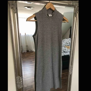  - Grå kort klänning med hög krage. Slits på sidorna. 