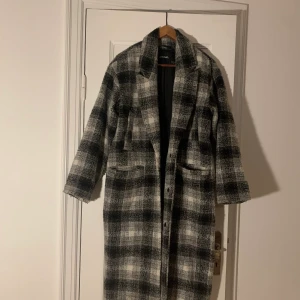 Rutig lång rock från Monki  - En grå/vit/svart-rutig rock från monki köpt ca 2 år sen. varm och lång! storlek XS (pris kan diskuteras vid snabb affär)