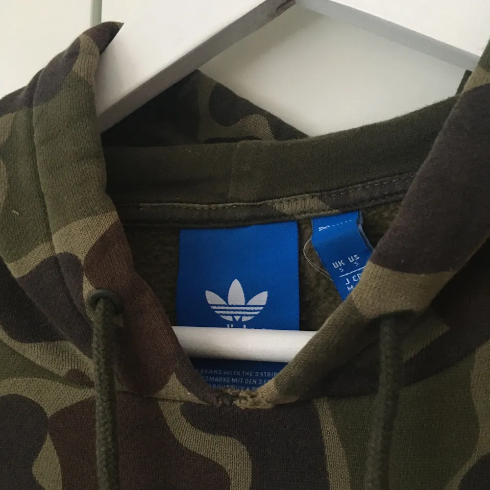Militärmönstrad/camouflage hoodie från Adidas i stl S. Herrmodell (passar inte på mig men visar passform på mig ändå). Köpt för ca 600 kr. Liten skada i kragen (bild nr 2). Frakt gratis, ingår i priset. . Hoodies.