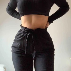  - Svarta kostymbyxor med raka ben hela vägen ner. Volangresår upptill med snörning. Inga fickor baktill däremot två fickor i sidorna. Storlek 34, alldeles för korta för mig som är 1,70.