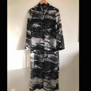  - Snygg, lång genomskinlig skjorta!  Melerad svart/vit.  På mig räcker den ner till anklarna och jag är 165cm.  Knäppning 2/3 uppifrån. Några decimeter slitsad i sidorna.  Perfekt på sommaren! 