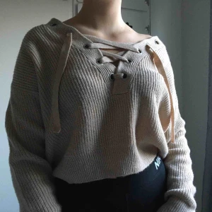  - Stickad tröja med snörning vid urringningen, ej använd