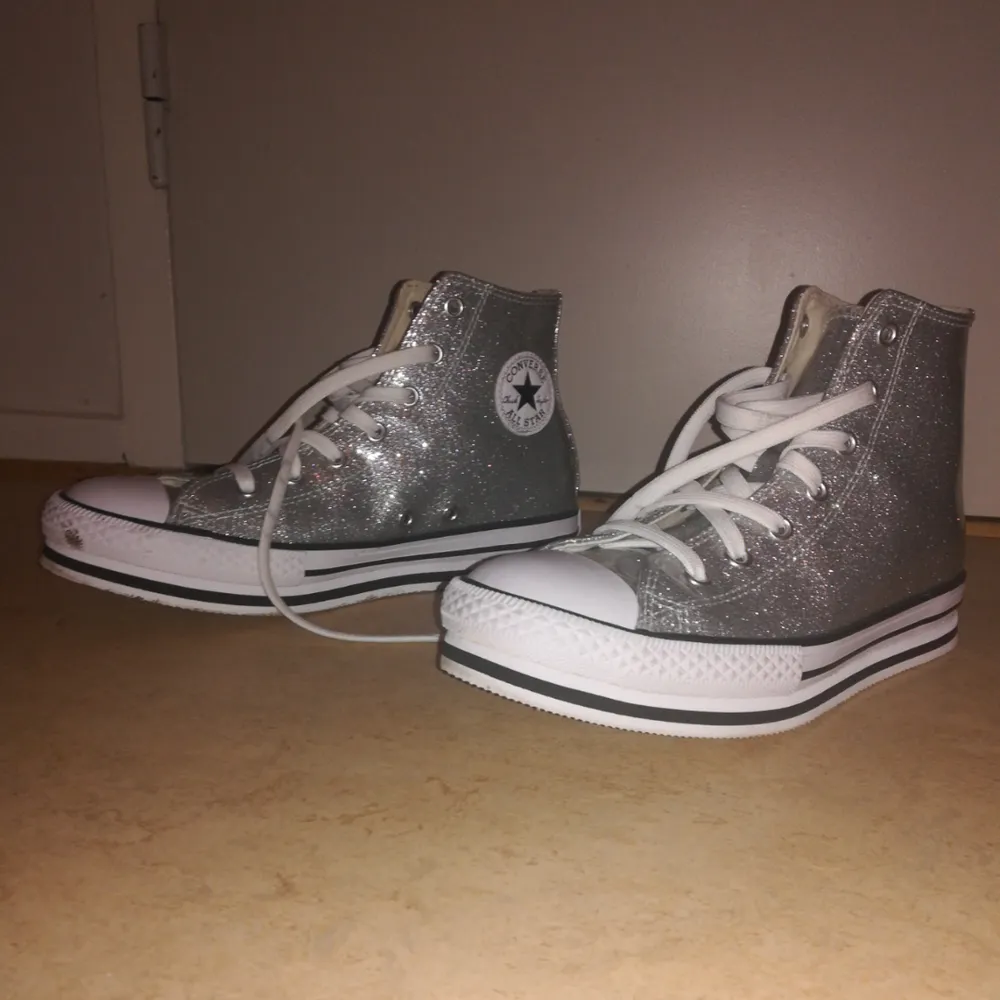 Silverglittriga Converse i plastaktigt material med liten platå. Köptes för en månad sen för 600:- och har använts en eller två gånger sen dess. Trivs inte i dem så säljer nu vidare 😊 priset kan diskuteras. . Skor.