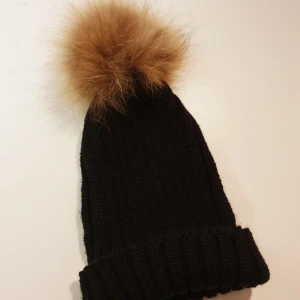  - Säljer denna svarta mössan med äkta pälsboll. Den har tyvärr inte kommit till användning men den är superfin och i toppenskick, har bara använt den 1 gång. Djur- och rökfritt hem. Köparen står för frakten. 