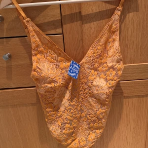 Body st M - Orange spetsbody, aldrig använd med prislappen kvar. I storlek M och nypris: 557kr