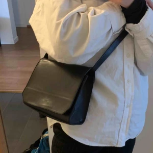  - Svart väska köpt på & Other Stories. Små synliga slitage på delen av väskan som hänger mot kroppen. I väskan är det ett stort fack, se 3e bilden. Bandet är 110cm långt, ej justerbart. Frakt tillkommer💌