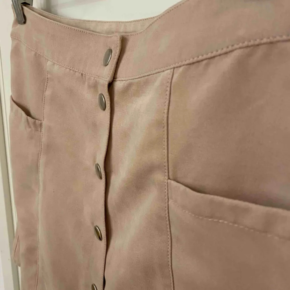 Gammalrosa kjol med knappar som öppning. Finns 2 främre fickor. Lent o mjukt tyg, använd ett fåtal gånger. . Kjolar.