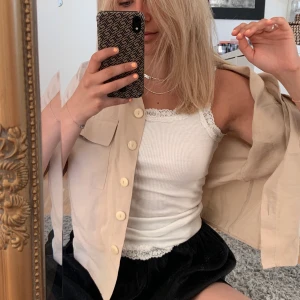 T-shirt skjorta från Zara - En beige T-shirt skjorta/blus från Zara i storlek M. 