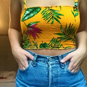 Orange croptop - En orange/gul mönstrad croptop från Nelly. Aldrig använd. Frakt ingår i priset. Passar som en S/M
