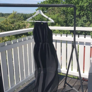 Svart klänning - Svart klänning med linneform upptill och resår i midjan. Knapp baktill. Från knä och nedåt är det tunnare tyg/ingen innerklänning 