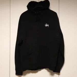 Svart Stussy hoodie - Svart Stussy hoodie med stort tryck på ryggen och litet på bröstet. Stl M