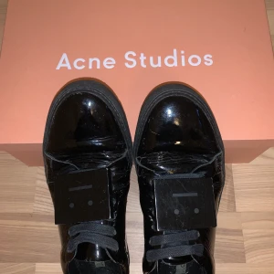 Acne sneakers - Svarta glansiga acne sneakers. Mycket använda med små repor man inte alls tänker på när man använder dom. Vänsterskon har gått upp lite i hälen men inget som syns när dom är på. Riktigt snygga till ett par långa raka jeans! Hade dustbags till båda men min kära mor har tyvärr slarvat bort dessa när hon vart ute och rest för att lägga sina andra skor i. Men lådan och ett par extra tillhörande skosnören får man med👍🏼 