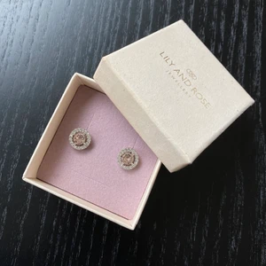 Lily and rose örhängen - Fina örhängen från Lily and rose. Dem är i silver med en ljusrosa sten i mitten. Använda under en skolavslutning, inprencip nya. Priset inkluderar frakten:)