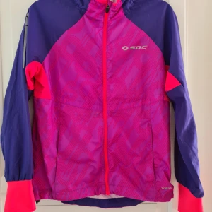 Modern Träningsjacka - Snygg träningsjacka som kan användas inne som ute. Härliga färger i rosa, lila och blå. Strl 146/152. Märke SOC. Mötas el köpare betalar frakt.