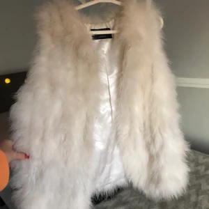 Väst  - En vit fluffig väst från Hollies! Använd Max 5 ggr! Finns inga slitningar eller missfärgningar. Ny pris 1999kr (Kan gå ner i pris vid snabbt köp)