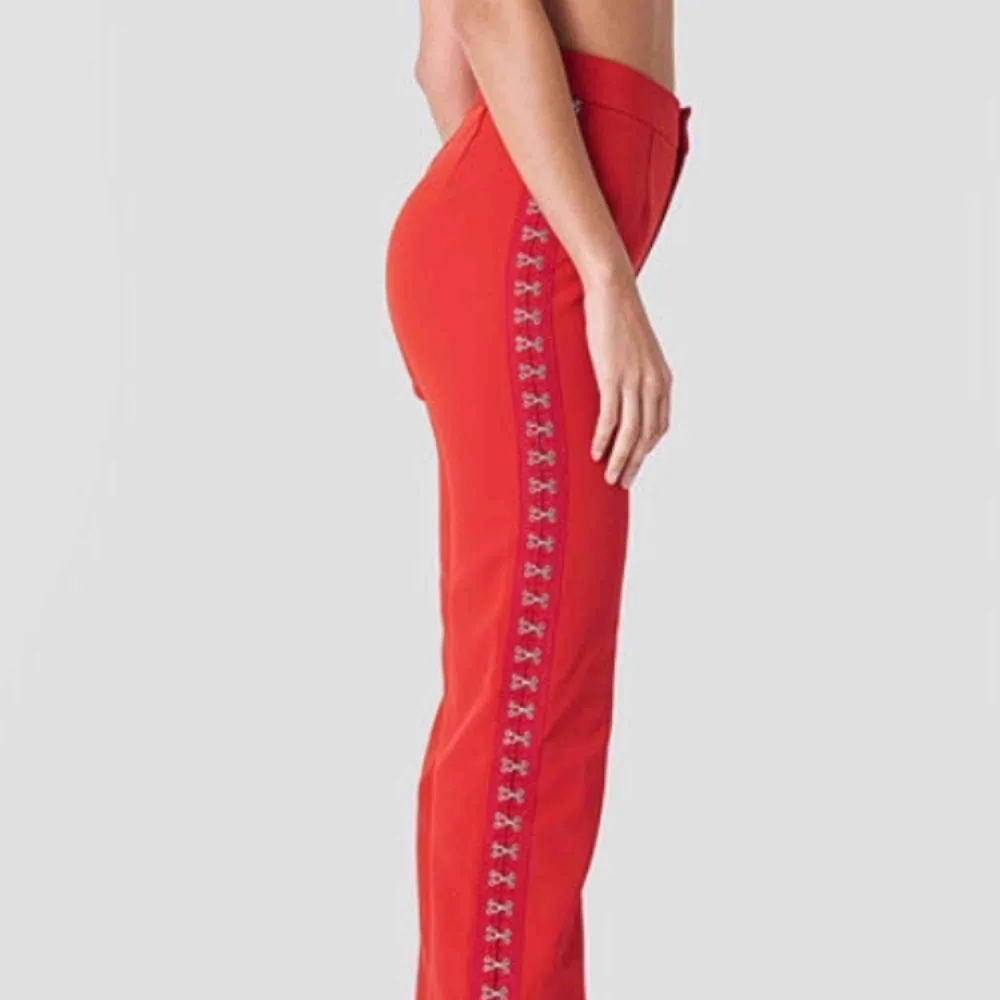 Snygga byxor från Sahara Ray’s kollektion för NAKD. Röda med hakor på sidorna som man kan dra upp om man vill ha slitsar i byxorna. De är röda & i perfekt skick. . Jeans & Byxor.