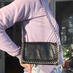  - Svart väska med silvriga detaljer. Köpt på scorett. Knappt använd och i fint skick. Den kan användas som både crossbody bag, kortare väska eller clutch Kan skicka fler bilder om det önskas. Köparen står för frakt. 