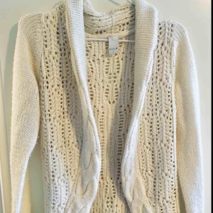  - Kofta i strl S med vacker kabelstickning och smickrande krage. Perfekt för både hemmakväll och på jobbet. Använd endast en gång. Nypris 600 kr