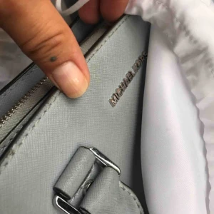  - En handväska från Michael Kors. Skick: 7/10. Modellen heter ’Selma Satchel’. Levereras i tillhörande dustbag. Finnes på Södermalm, Stockholm. Kan postas men då står Du för frakten, (110kr). Mvh Marija & Nugget