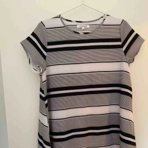  - T-shirt klänning, A-linjeformad, svart och vit randig.   Köparen står för porto. 