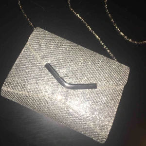  - Silvrig glitterväska med ett stort fack och en liten ficka. Går att bära med eller utan axelbandet. Säljer på grund av att jag inte använder den. Använt 1-3 gånger. Använde bland annat på min bal där den passade jättebra. 