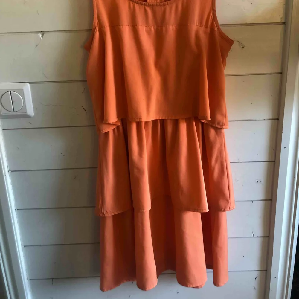Orange klänning med volanger, köpt på torp för tre/fyra år sedan. Använd 1 gång! Köparen står för frakten. Klänningar.