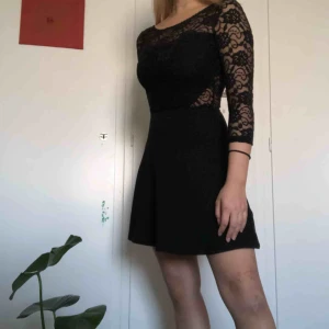  - Fin svart klänning med spets på överdelen samt dubbelt lager tyg vid brösten och magen. Lite stretchig, trekvarts långa ärmar, lite tajt på överdelen som formar midjan lite. Går ner till lite ovan knäna, jag är 160cm lång.