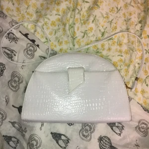 Handväska - Vit handväska med ormmönster och unik form. Jättehäftig men säljer pga har inte kommit till användning för mig. Frakt på 63kr tillkommer