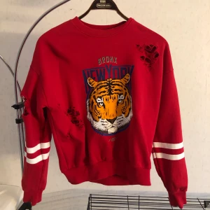 Röd sweatshirt S - Röd sweatshirt med tigermotiv fram, vita ränder på armarna. 