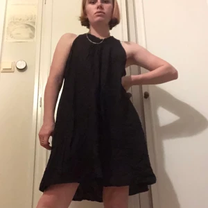 En svart klänning - En svart klänning med broderi som band. V-ring. Storlek XL.