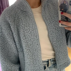 blå teddytröja från BikBok - storlek XS. Har en dragkedja, polo, fickor och man kan göra den mindre samt större i midjan. Otroligt skön! säljer pg.a har bytt stil sedan jag köpte den :(