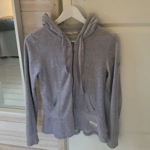 Odd Molly kofta strl 1 (XS-S) - Ljusgrå Odd Molly kofta med två silkes snörningar samt två fickor. I ryggen där volangen börjar sitter en liten rosa rosett. Välfungerande dragkedja. Ordinarie pris 1200kr. Mycket fint skick men har använts väl. Passar folk vid 160-170