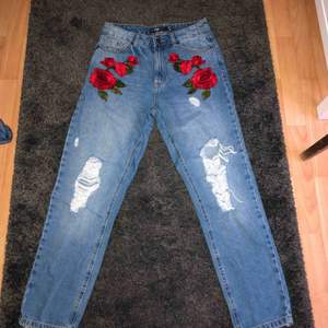 Jeans med slitningar och rosor som detaljer