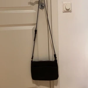 Axelväska  - Svart axelväska med justerbar axelrem. Knappt använd och säljer då den inte kommer till användning:) Pris kan diskuteras.