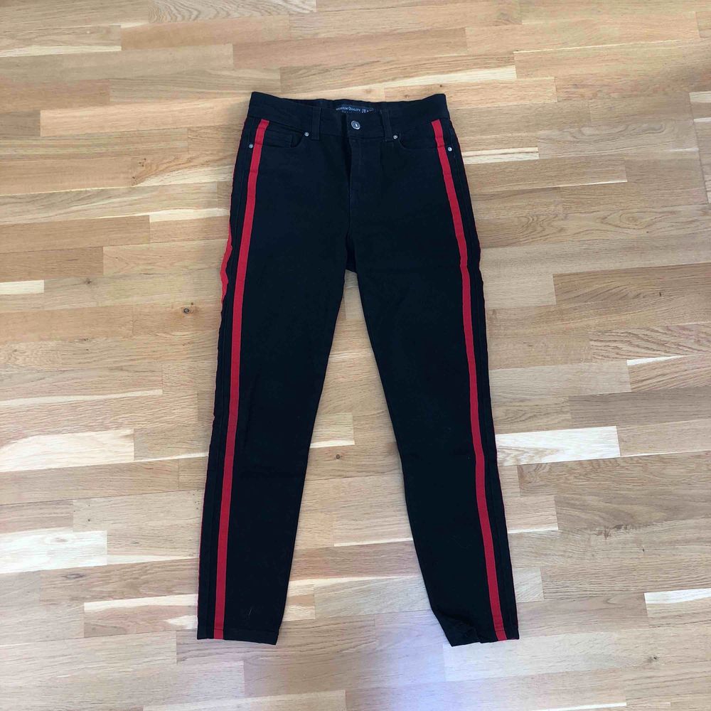Svarta jeans med två röda streck på varje ben längs med sidorna. Högmidjade. Mom fit modell. Använd endast enstaka gång, som nya. Fint skick. Frakt tillkommer. Jeans & Byxor.