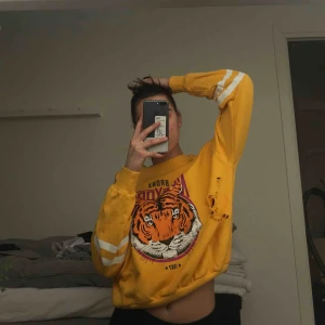  - Gul sweatshirt med ett lejon på